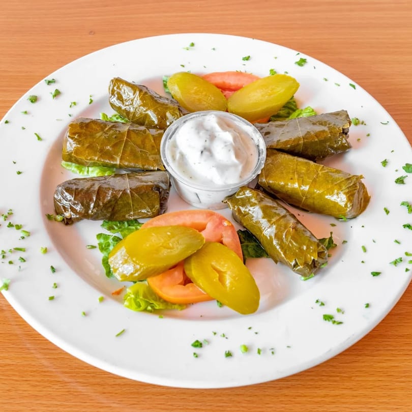 Fanoos Grill's Dolmeh, grape leaves stuffed with rice and herbs, served with pickles and yogurt dip.
