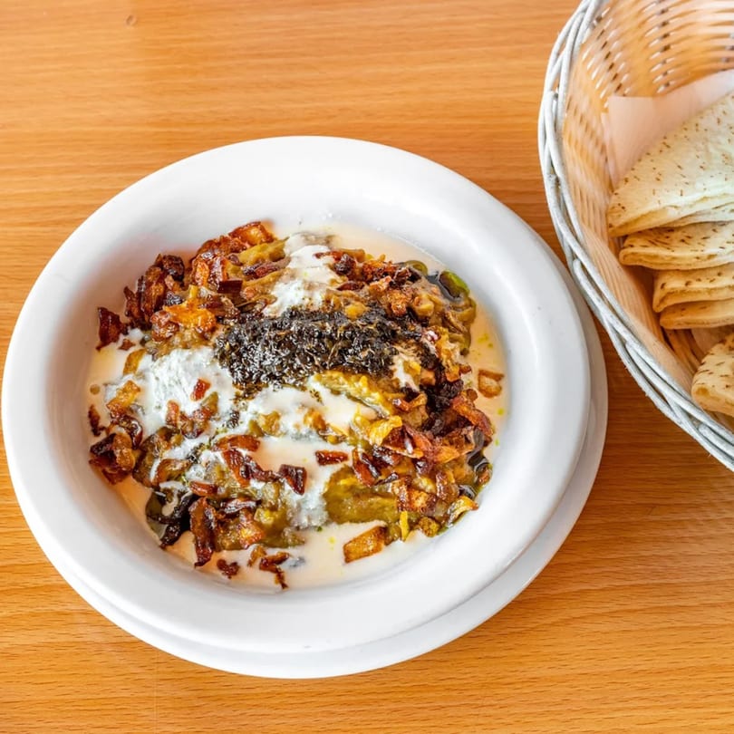 Persian Kashk Bademjan, an eggplant dip topped with fried onions, mint, and a side of flatbread.